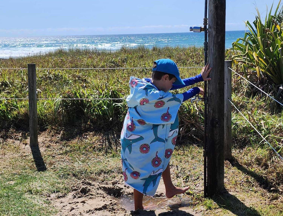 Young boy washing the sand off his feet before he gets in the car, note, no need to shake the Feeding Frenzy sand less beach towel as the tight knit is sand resistant