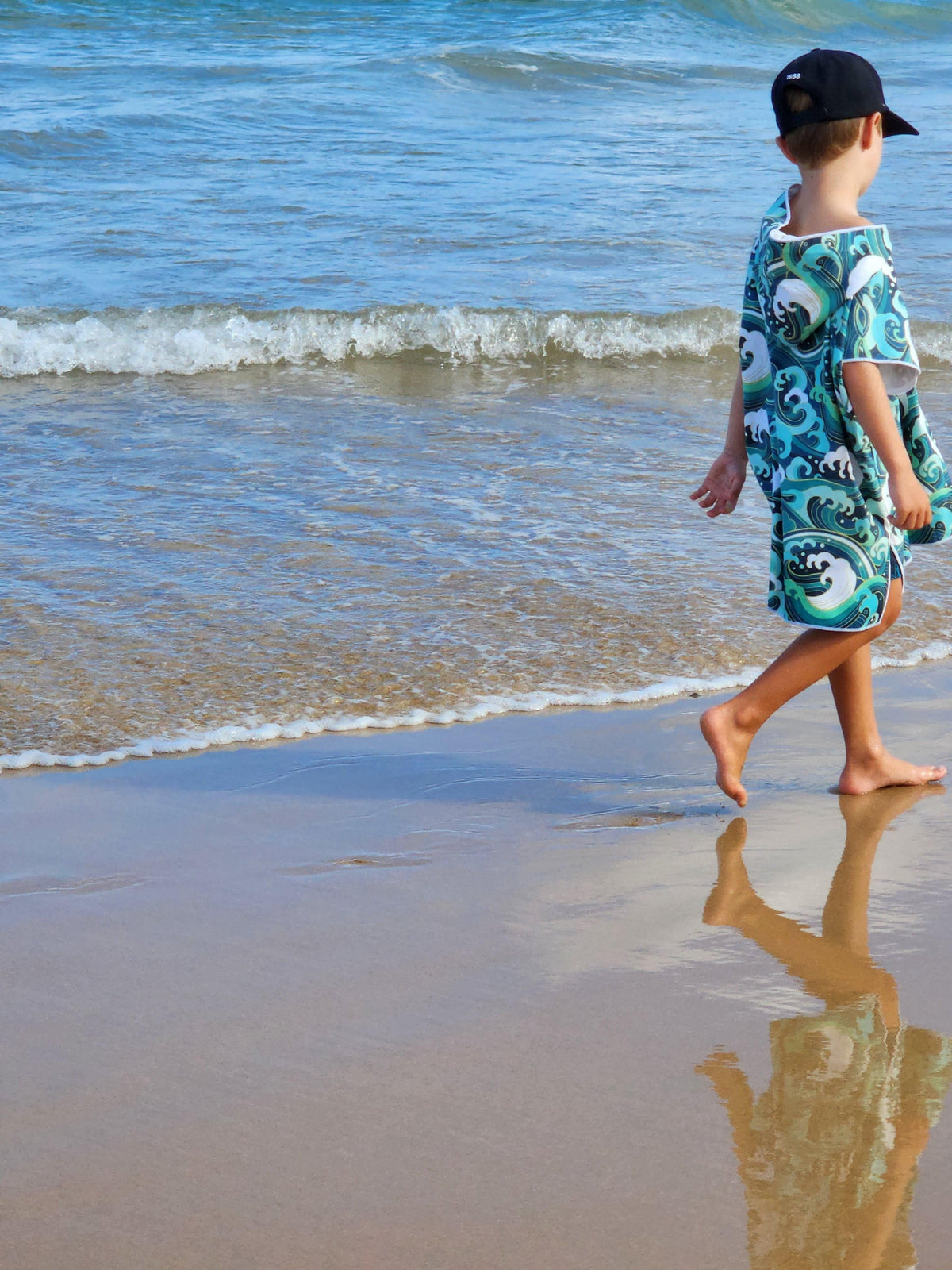Yound boy walks along Currumbin Beach wearing his Wipeout designed towel he is approx 6 years old and wears the medium size
